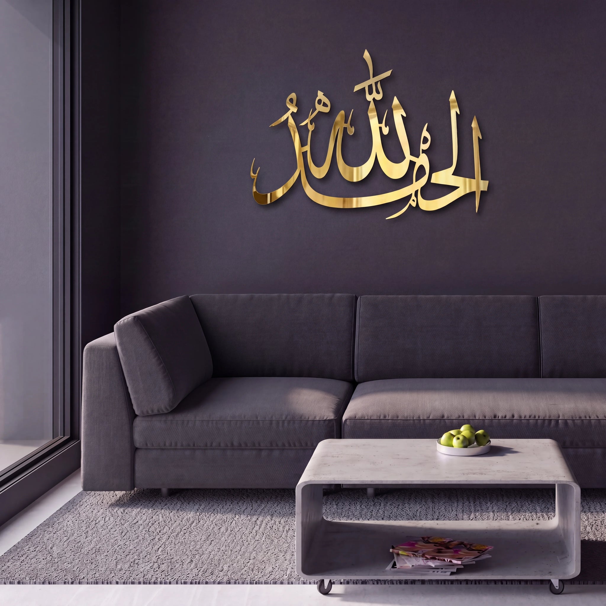 Shiny Gold Alhamdulillah Arabic calligraphy wall art mounted on a dark gray wall above a modern gray sofa and concrete coffee table.