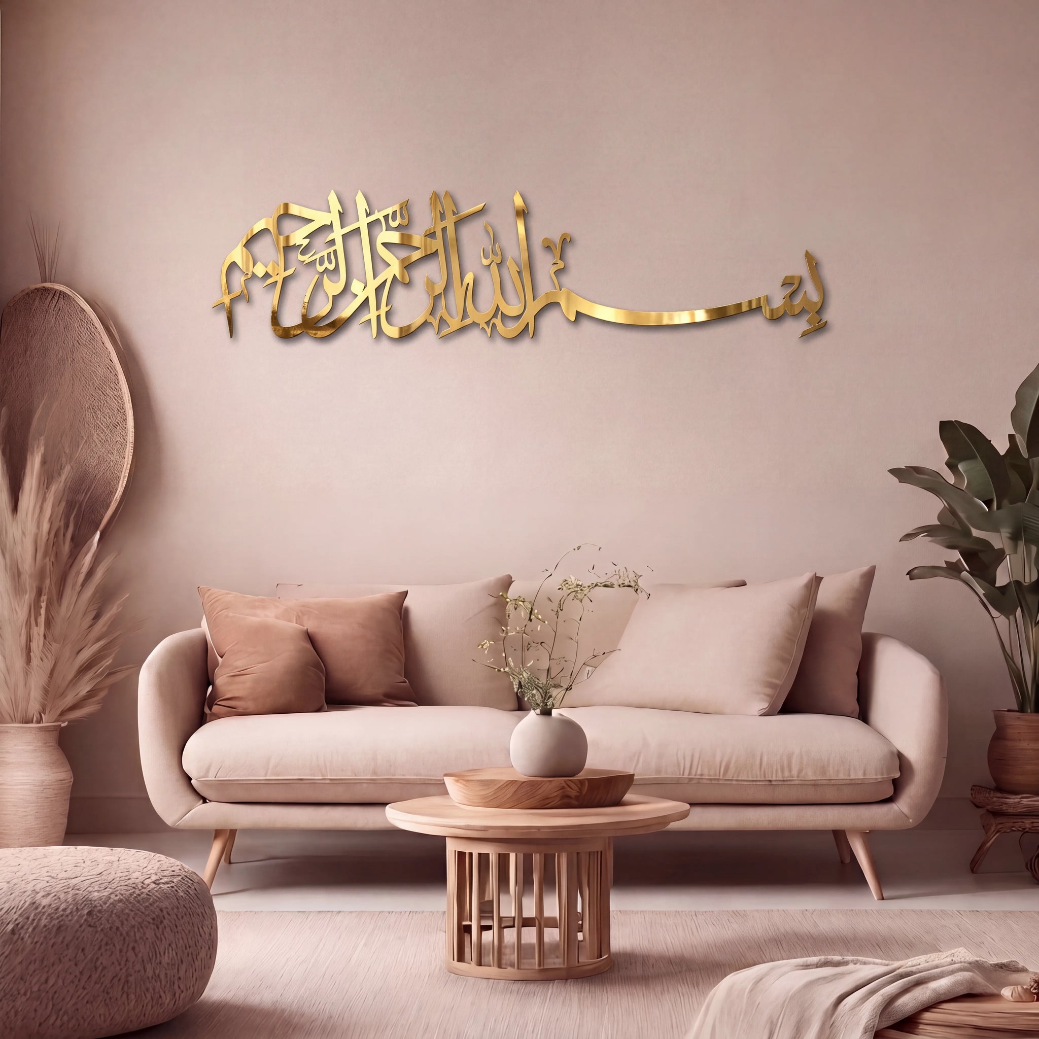 Gold Bismillah Arabic calligraphy wall art mounted on a beige wall above a light beige sofa in a styled living room with a wooden coffee table, cushions, and potted plants.