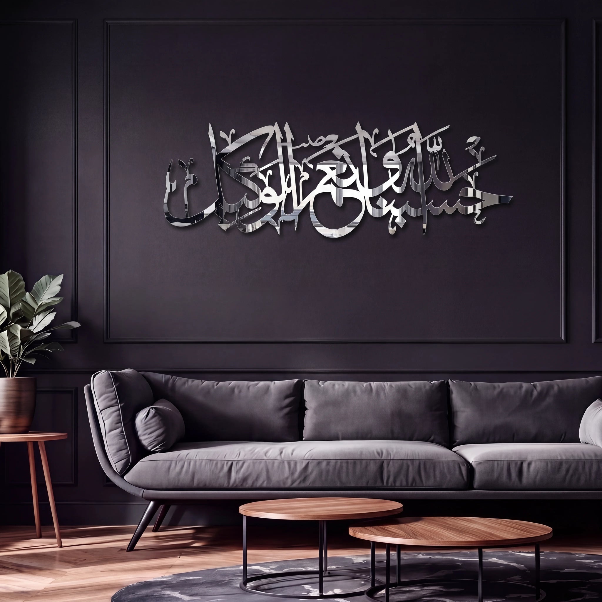 A modern living room with a dark gray sofa, wooden coffee tables, and a black paneled wall featuring large reflective Chrome Silver metallic Arabic calligraphy wall art.