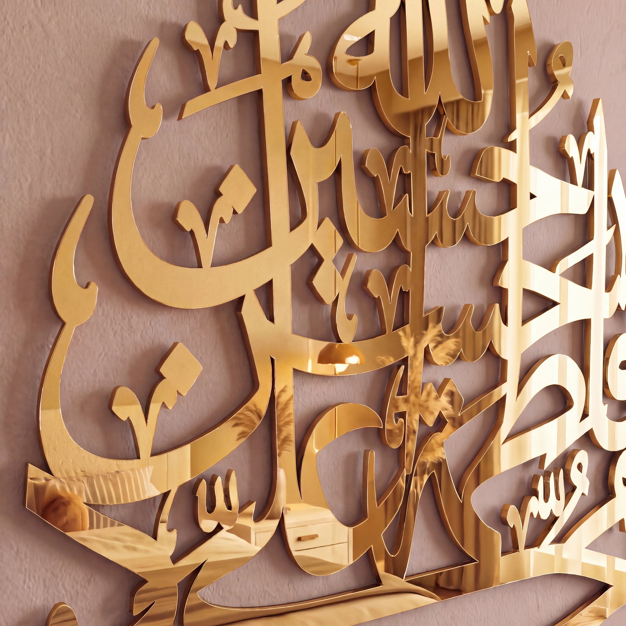 Gold metallic Arabic calligraphy wall art mounted on a textured beige wall.