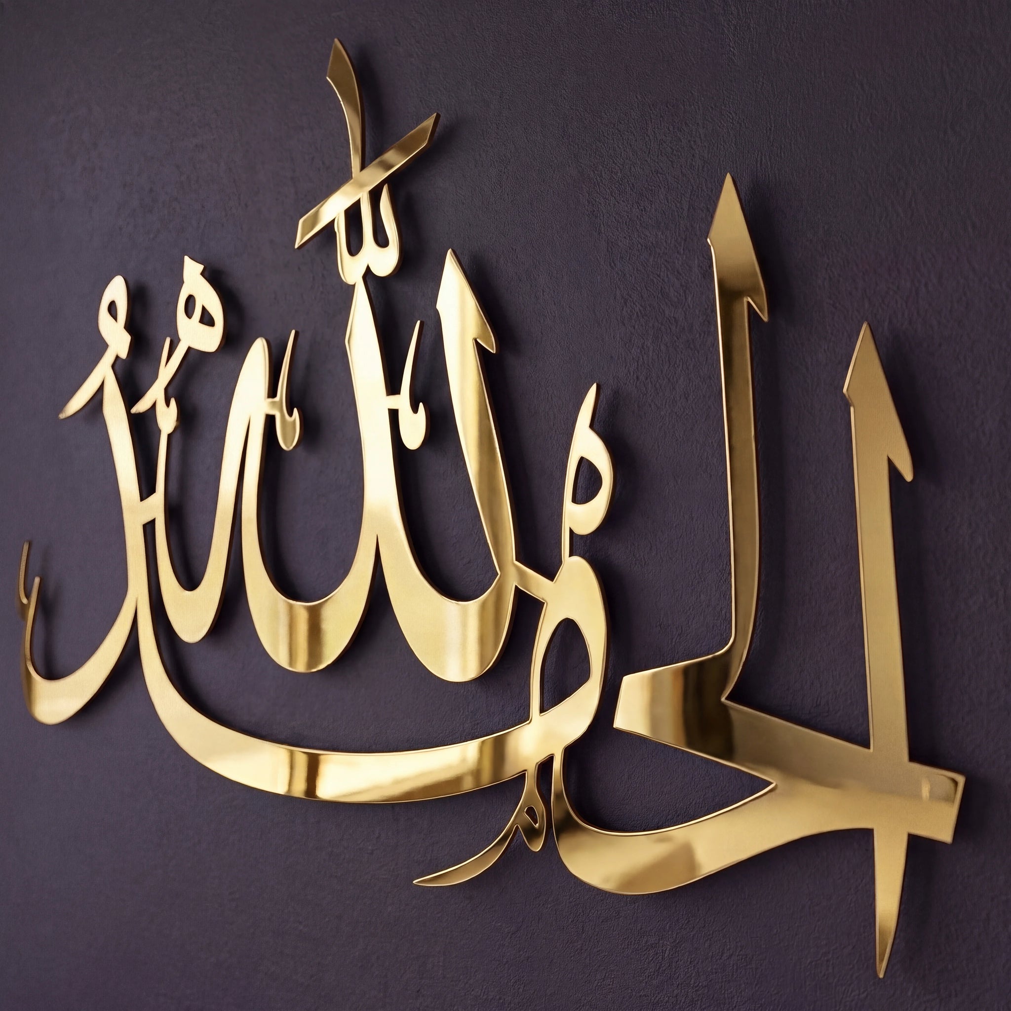 Shiny Gold metallic Arabic calligraphy wall art mounted on a dark textured wall.