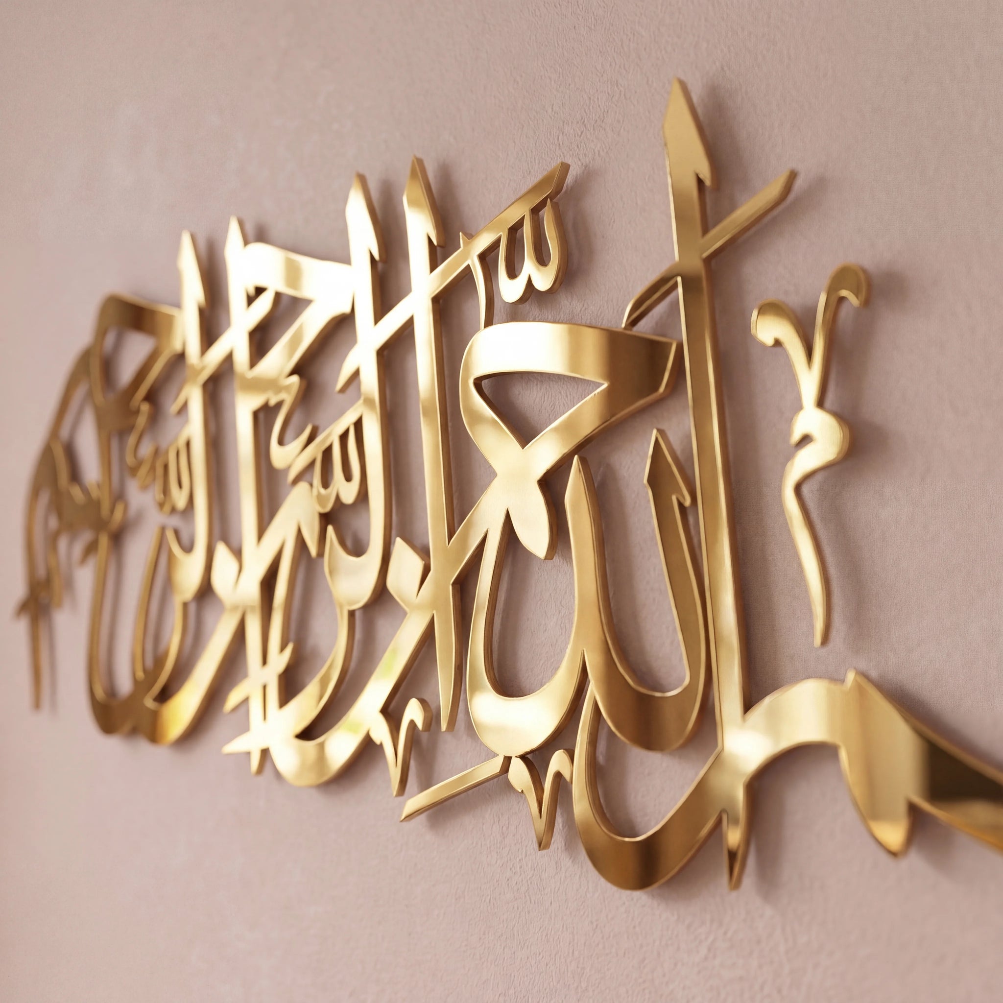 Gold Bismillah metallic Arabic calligraphy wall art mounted on a light beige wall.