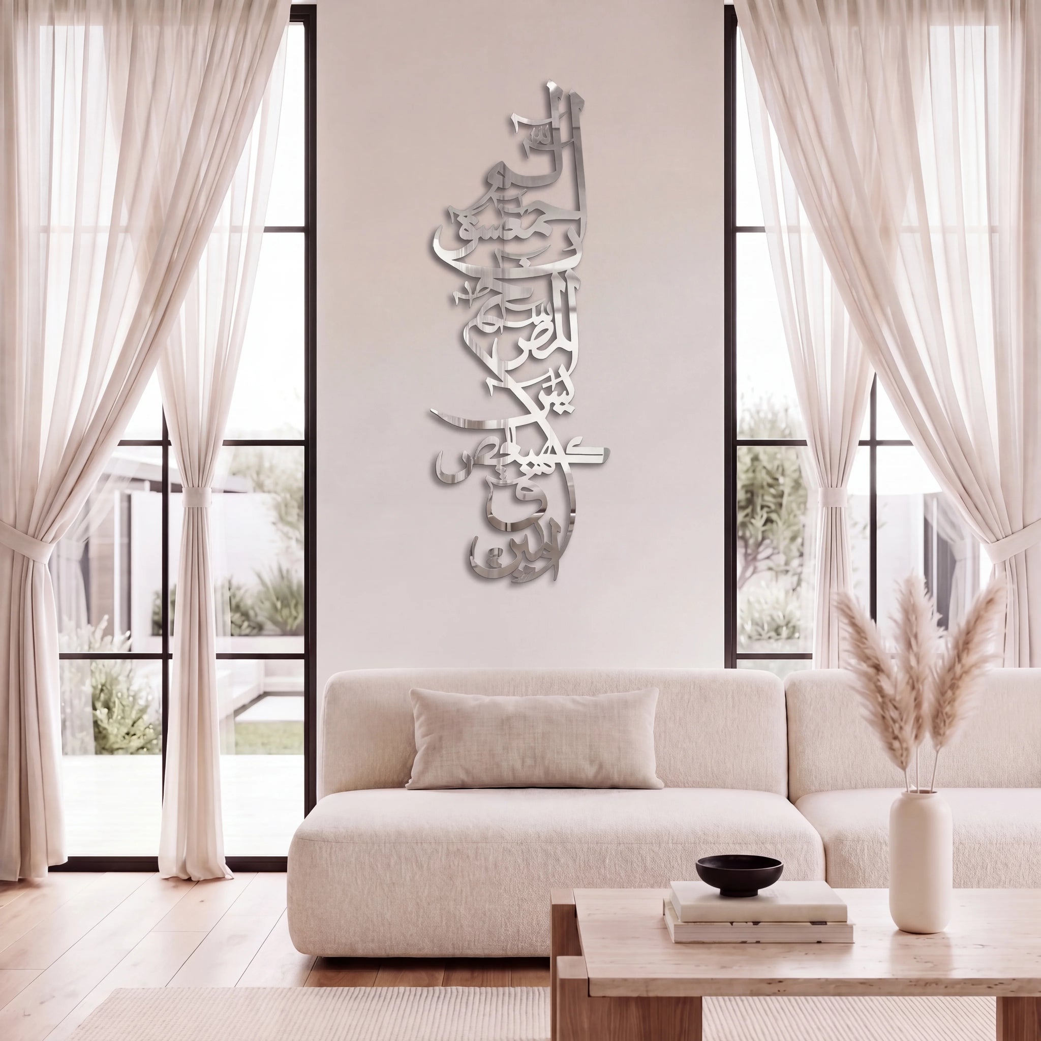 Chrome Silver Lohe Qurani Arabic calligraphy wall art mounted on a light beige wall above a modern cream-colored sofa in a bright, contemporary living room.