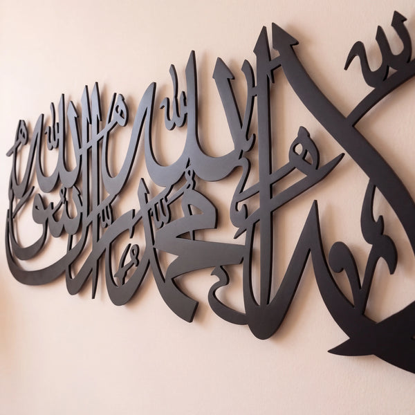 Shahada Kalima Black metal Islamic wall art featuring Arabic calligraphy, mounted on a light beige wall.
