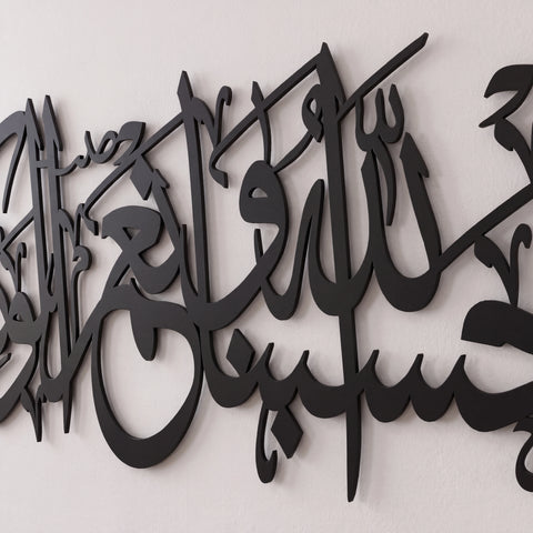 Black Quran Ayat metal Arabic calligraphy wall art mounted on a light off-white textured wall.