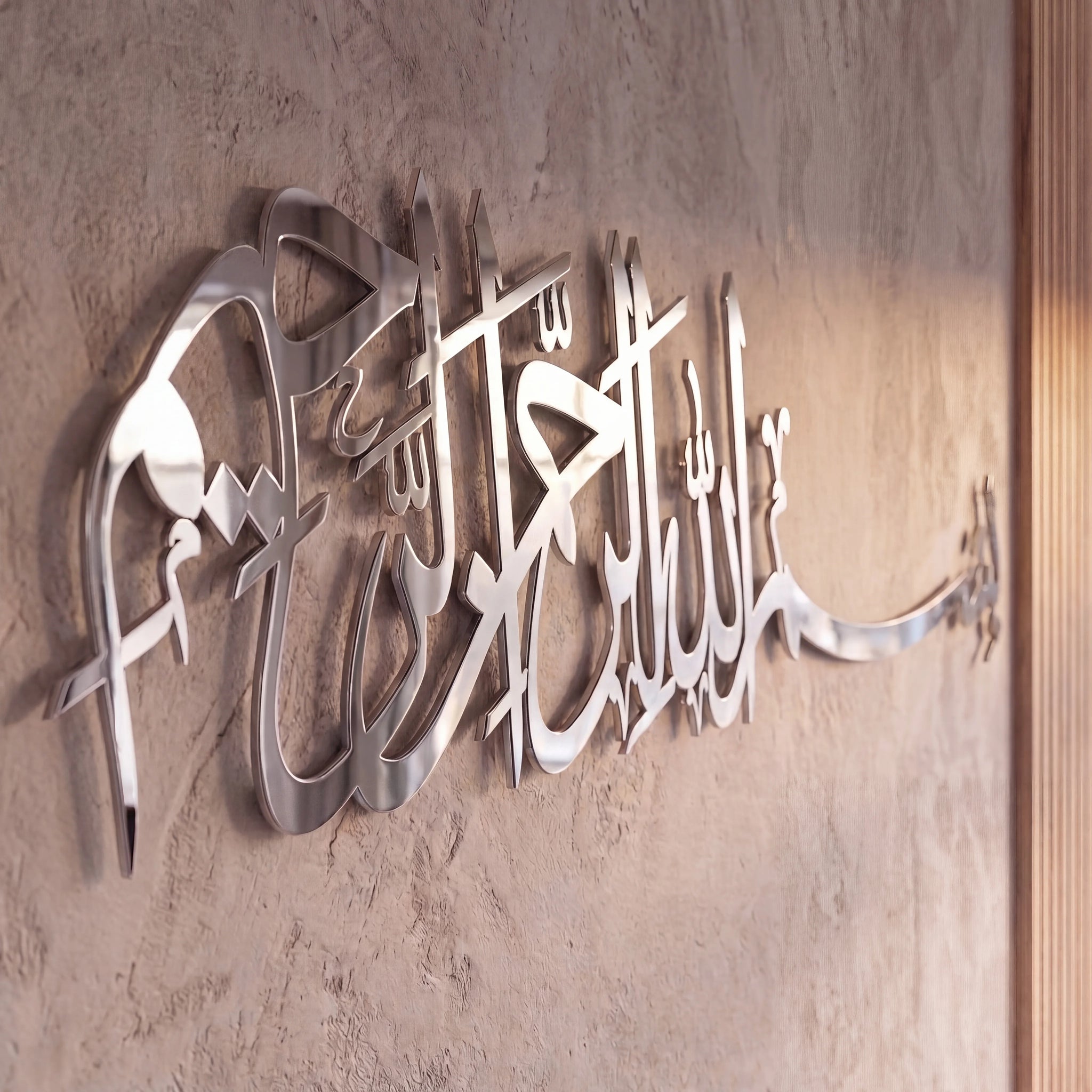 Chrome Silver metallic Bismillah Arabic calligraphy wall art mounted on a textured beige plaster wall.