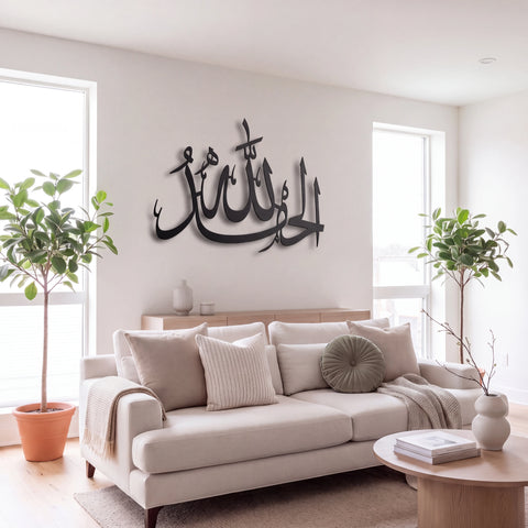 Black Alhamdulillah metal Arabic calligraphy wall art mounted on a light beige wall above a modern beige sofa in a bright, contemporary living room.
