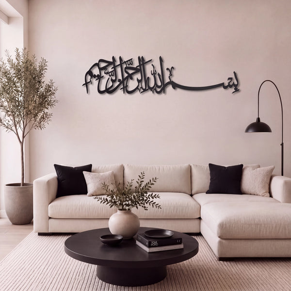 Black Bismillah metal Arabic calligraphy wall art mounted on a beige wall above a modern beige sectional sofa in a styled living room.