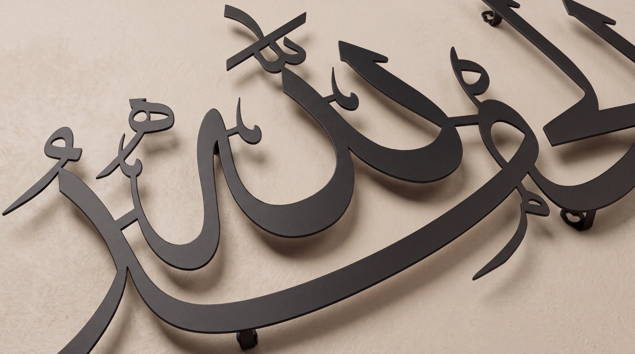 Black metal Arabic calligraphy wall art mounted on a beige textured wall.