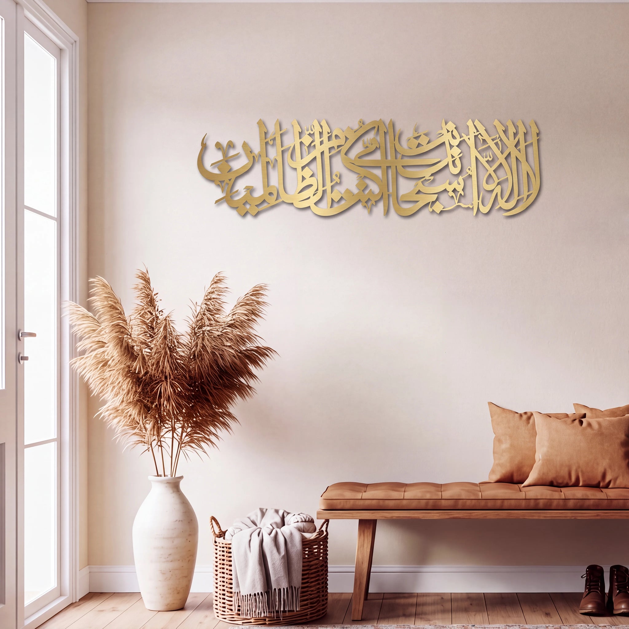 Mate Gold Ayat Kareema Arabic calligraphy wall art mounted on a beige wall in a styled living room setting with a bench, pampas grass in a vase, and a basket.