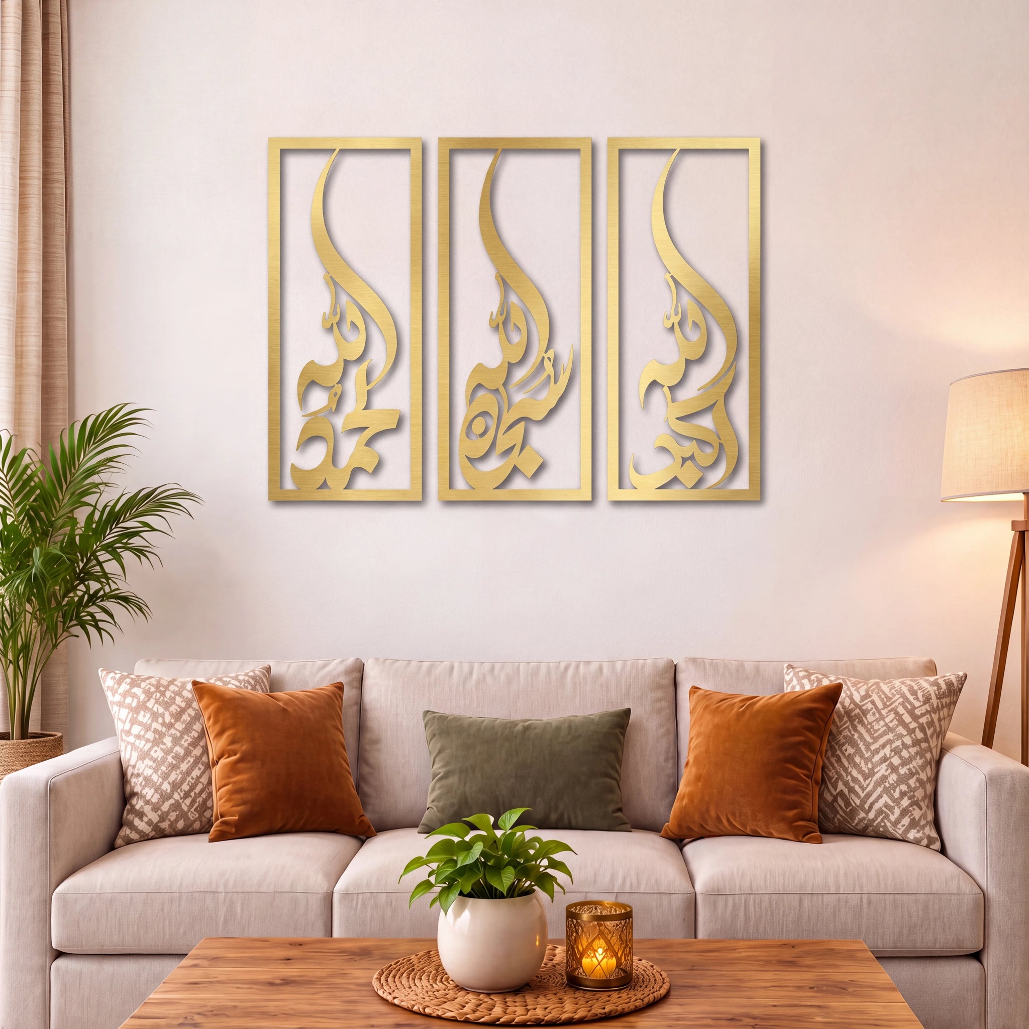 Three vertical Subhanallah Alhamdulillah Allah Ho Akbar Mate gold-framed wall art panels with abstract cutout designs, displayed above a beige sofa in a styled living room with pillows, a coffee table, and plants.